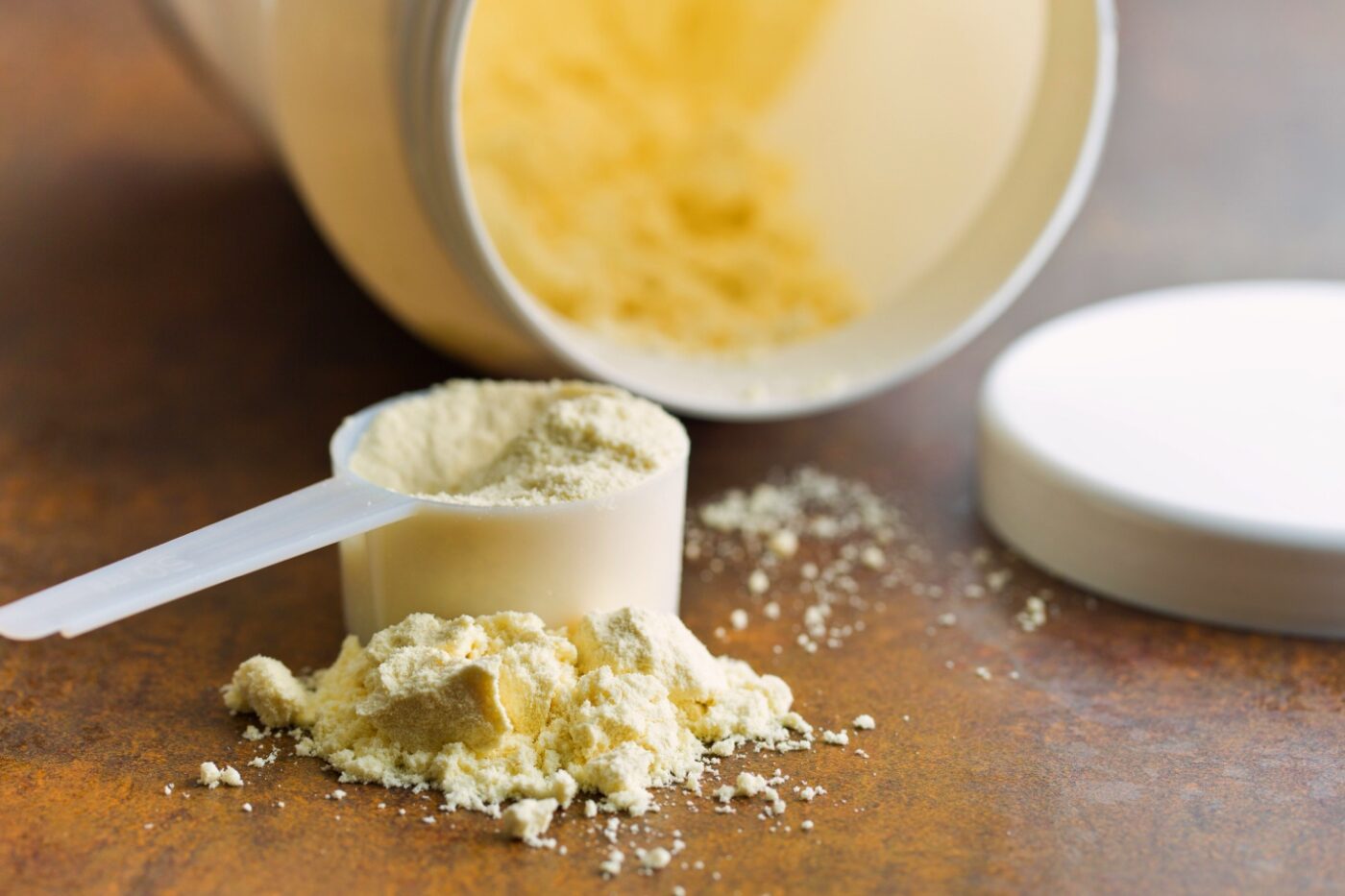 protein powder in a scoop with container on its side