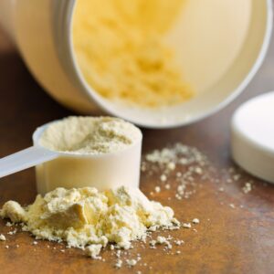 protein powder in a scoop with container on its side